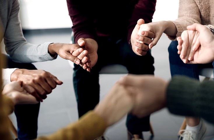 A diverse group holding hands together in prayer